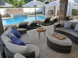 Ein Poolbereich mit Liegestühlen, einer Sitzecke und Sonnenschirmen.