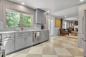 A modern kitchen with grey cabinets, a marble countertop, and a large window. - Luxe 5BR Atlanta Retreat in Buckhead (Atlanta)