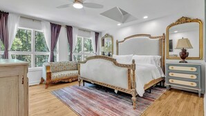 Une chambre à coucher comprenant un lit, un canapé, une commode, un miroir et un ventilateur de plafond.