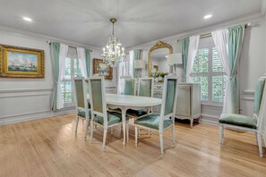 A dining room with a white table, green upholstered chairs, a chandelier, and a large mirror. - Luxe 5BR Atlanta Retreat in Buckhead (Atlanta)