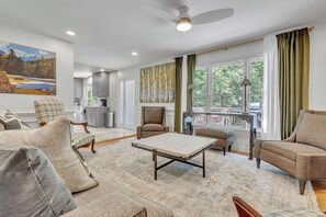 A spacious living room with a large window, a ceiling fan, and a view of the outdoors. - Luxe 5BR Atlanta Retreat in Buckhead (Atlanta)
