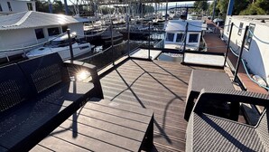 Une terrasse sur le toit offrant une vue sur une marina, avec des bateaux et un espace abrité.