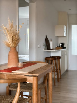 Ein Holztisch mit einer Vase gefüllter Trockensaat, einer roten Tischmatte und gewobenen Stühlen.