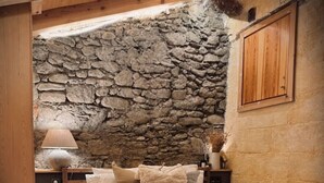 A bedroom with a stone wall, wooden bed frame, and a wooden cabinet. - Ático-Loft con encanto en el Centro de Camprodon (Camprodon)