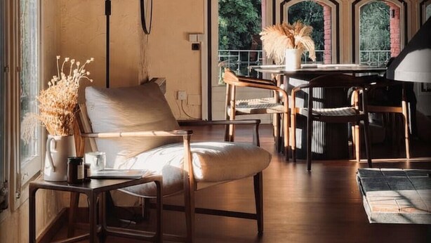 A cozy room with a sofa, chairs, a table, and a lamp. There are windows with views of greenery. - Ático-Loft con encanto en el Centro de Camprodon (Camprodon)