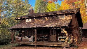 A rustic cabin with a porch, a chimney, and a stone fireplace. - Cozy 1-bedroom log cabin in beautiful Manitowish Waters/Winchester (Manitowish Waters)