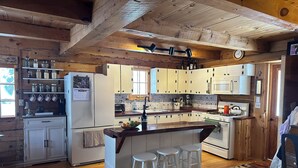 A kitchen with wooden beams, white cabinets, a central island with stools, and a microwave. - Cozy 1-bedroom log cabin in beautiful Manitowish Waters/Winchester (Manitowish Waters)