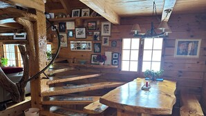 A wooden interior with a spiral staircase, wooden dining table, and walls adorned with framed photos. - Cozy 1-bedroom log cabin in beautiful Manitowish Waters/Winchester (Manitowish Waters)