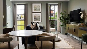 A modern living room with a round table, sofa, and TV. - Mill Court Escape & Swimming Pool (Dunblane)