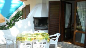 An outdoor dining area with a table, chairs, and a barbecue grill. - Townhouse With Enclosed Private Garden (San Michele al Tagliamento)