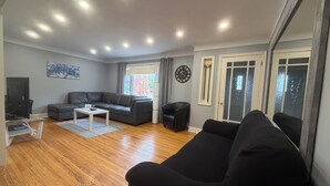 Un salon moderne avec un canapé, une table basse, un téléviseur et une grande fenêtre.