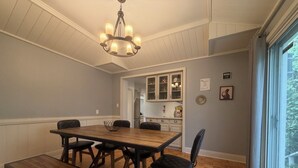 Un coin repas avec une table en bois, des chaises et un lustre.
