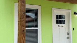A green building with a white door labeled 'Decatur,' a window with blinds, and a wooden post.