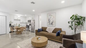 A modern living room with a sofa, coffee table, and dining area.
