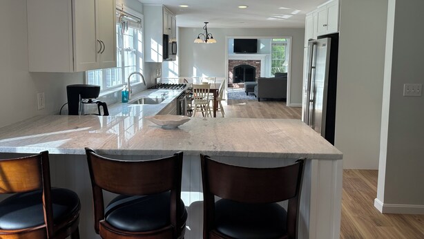 A modern kitchen with a large island, bar stools, pendant lighting, and a fireplace. - Spacious 4 bedroom PRIVATE HOME
centrally located to all the Cape has to offer (Barnstable)