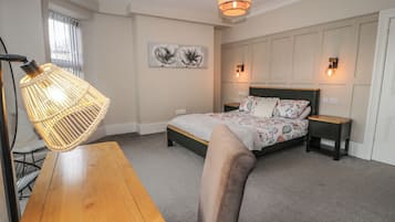 A bedroom with a bed, bedside tables, a lamp, a wall art piece, and a window.
