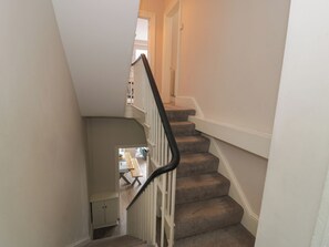 A staircase with carpeted steps and a white handrail, leading to an upper floor. - Llety Clyd (Barmouth)