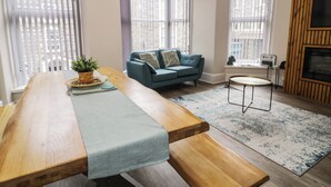 Ein modernes Wohnzimmer mit einem Holzes Esstisch, einem blauen Sofa und einem kleinen runden Tisch.