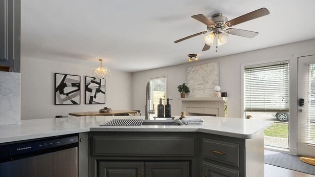 Una cucina con lavastoviglie, ventilatore a soffitto, lavello e schienale in marmo.