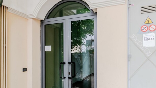 A hotel entrance with a glass door, a metal staircase, and a warning sign. - GuestHost - Seaside Sanctuary with balcony and parking (Rimini)