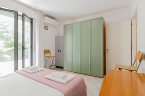 A bedroom with a bed, a desk, a chair, a wardrobe, and a sliding glass door leading to a balcony. - GuestHost - Seaside Sanctuary with balcony and parking (Rimini)
