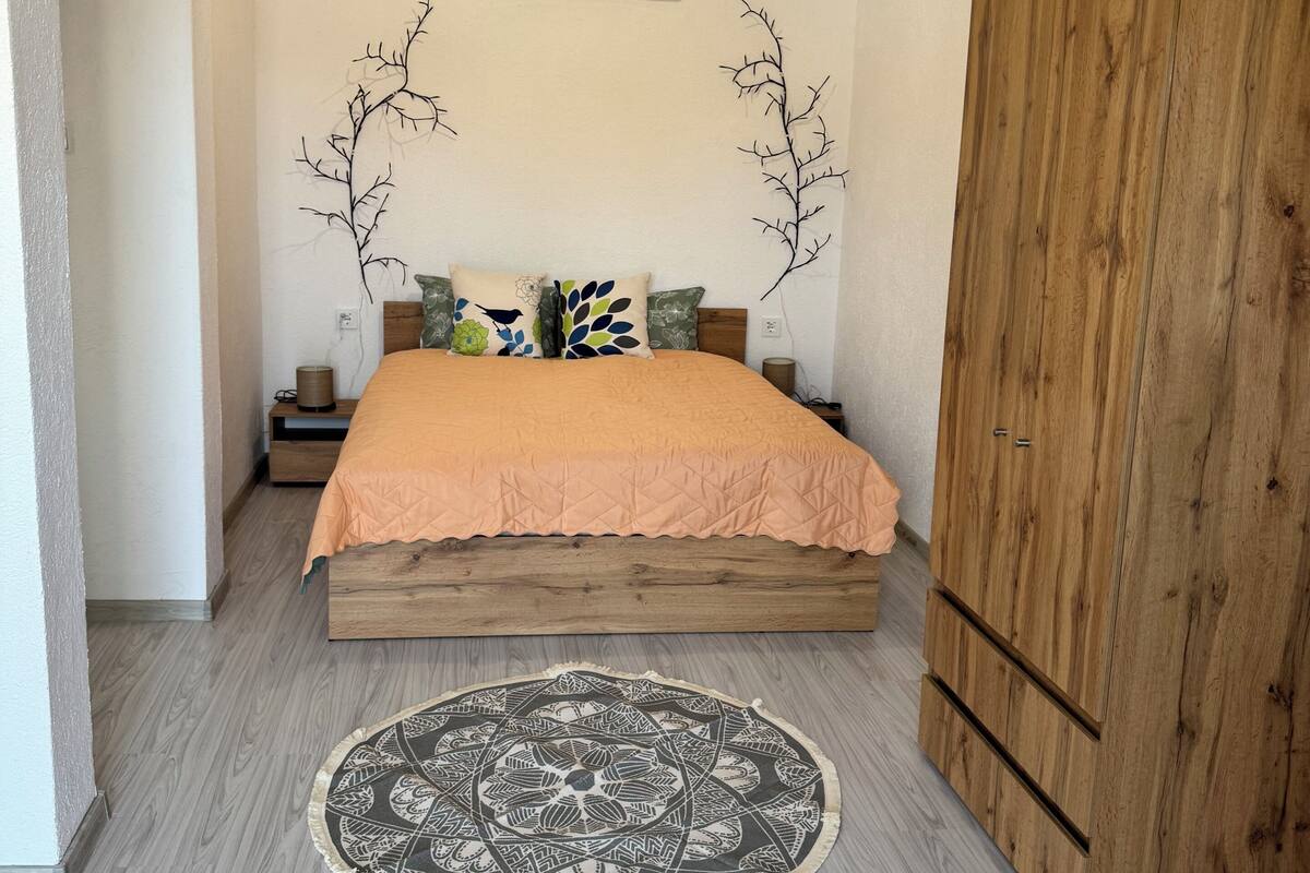 A bedroom with a bed, a round rug, a wardrobe, and wall decorations.