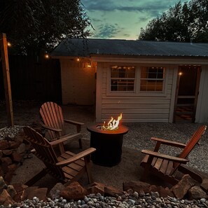 A wooden deck with two Adirondack chairs and a fire pit.