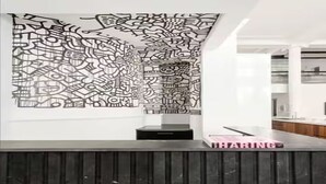 A modern interior with a patterned wall, a dark wooden panel, and a pink book titled 'SHARING' on a counter. - 8,000 sq ft, 7BR/8.5BA triplex maisonette with 3 private entrances (New York)
