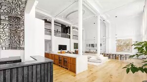 A spacious interior with high ceilings, a central island, and a large window. - 8,000 sq ft, 7BR/8.5BA triplex maisonette with 3 private entrances (New York)