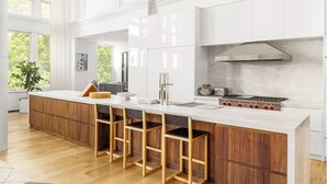A modern kitchen with a large island, bar stools, a stove, and a view of greenery outside. - 8,000 sq ft, 7BR/8.5BA triplex maisonette with 3 private entrances (New York)