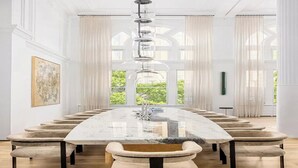 A long dining table with chairs, a hanging light fixture, and a view through large windows. - 8,000 sq ft, 7BR/8.5BA triplex maisonette with 3 private entrances (New York)