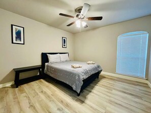 Ein Schlafzimmer mit Bett, Deckenventilator und Fenster mit Jalousien.
