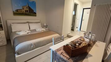 A hotel room with a bed, bedside table, and a view of a building through the window.