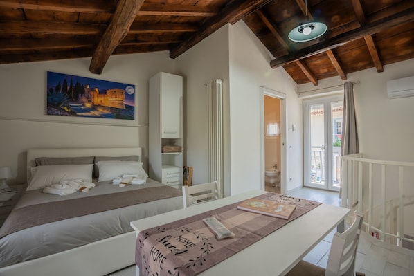 Ein Schlafzimmer mit Bett, Nachttischen, einem Gemälde und Blick ins Freie.