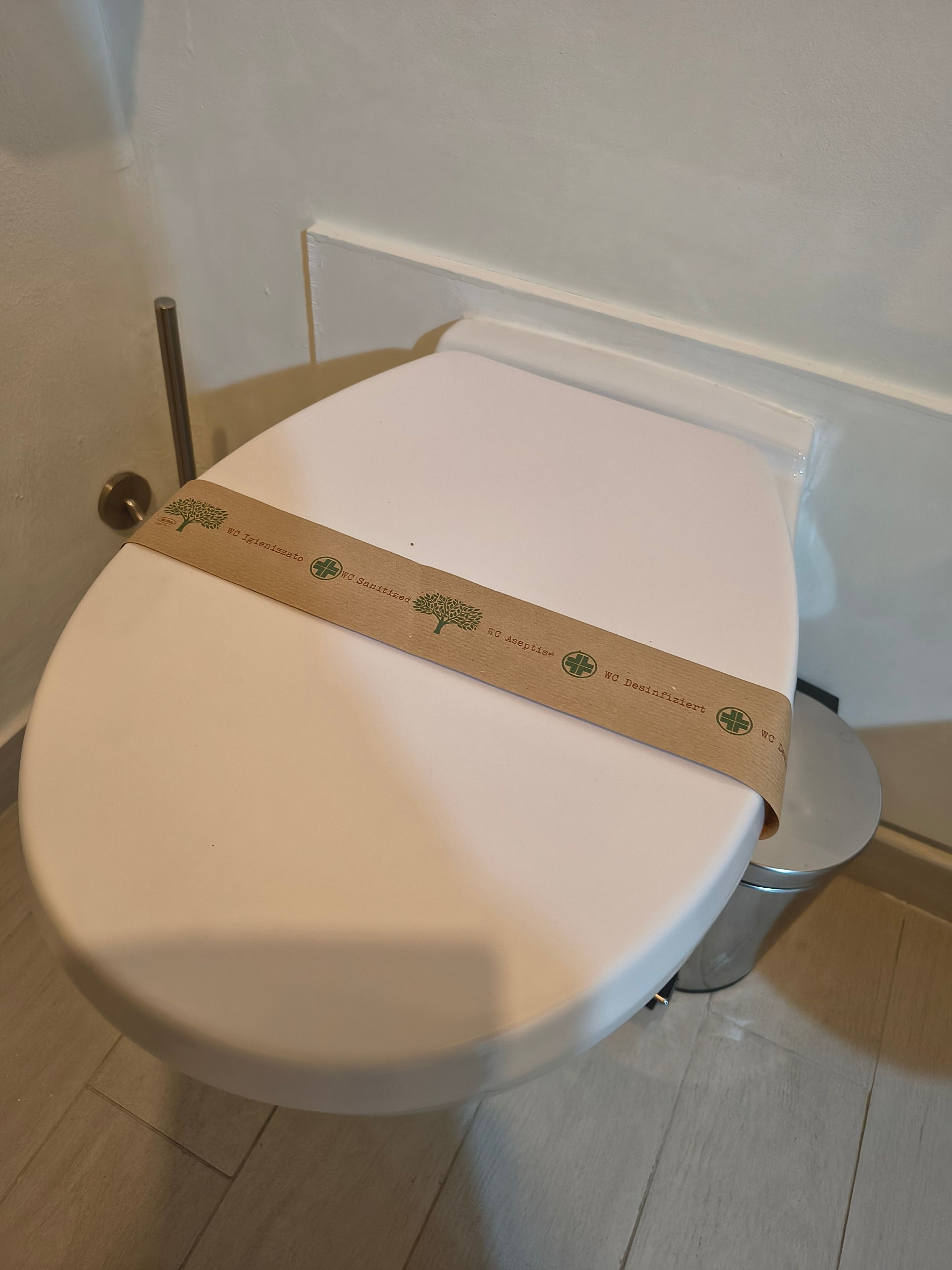 Un inodoro con una franja de papel marrón sobre el asiento, que indica que ha sido sanitizado.