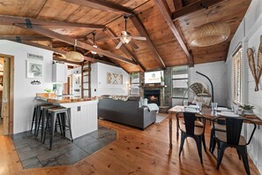 A spacious loft with exposed wooden beams, a fireplace, a dining area, and a cozy seating area. - Whispering Bass Lodge 3BDR (Kimberling City)