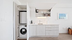 A compact kitchen with a washing machine, a microwave, and a sink. - 6080 Collins  (Miami Beach)