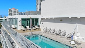 A rooftop pool with lounge chairs and a glass-enclosed area. - 6080 Collins  (Miami Beach)