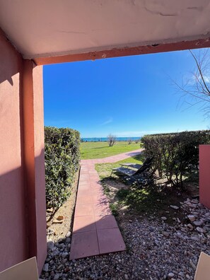A pathway leading to a grassy area with a view of the sea, a hedge, and a clear blue sky. - Cosy studio with sea & garden view - swimming pool (Sète)