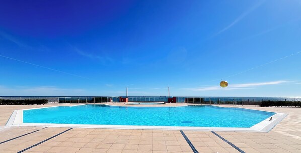 A rectangular outdoor swimming pool with clear blue water, surrounded by a tiled deck. - Cosy studio with sea & garden view - swimming pool (Sète)