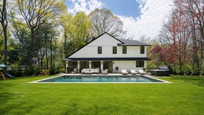 Une maison à deux étages avec une piscine, un patio doté de chaises longues et un toboggan dans le jardin.