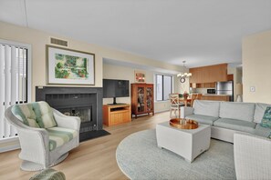 Ein Wohnzimmer mit Kamin, einer Couch, einem Fernseher und einem Essbereich.