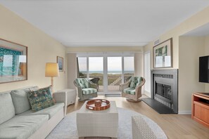 Ein Wohnzimmer mit einer Couch, zwei Sesseln, einem Couchtisch, einem Kamin und einem Fernseher.