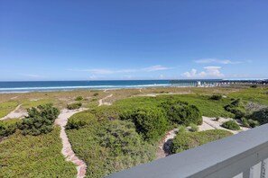 Blick auf die Küste mit Strand, einem Steg und einem Weg durch die Dünen.