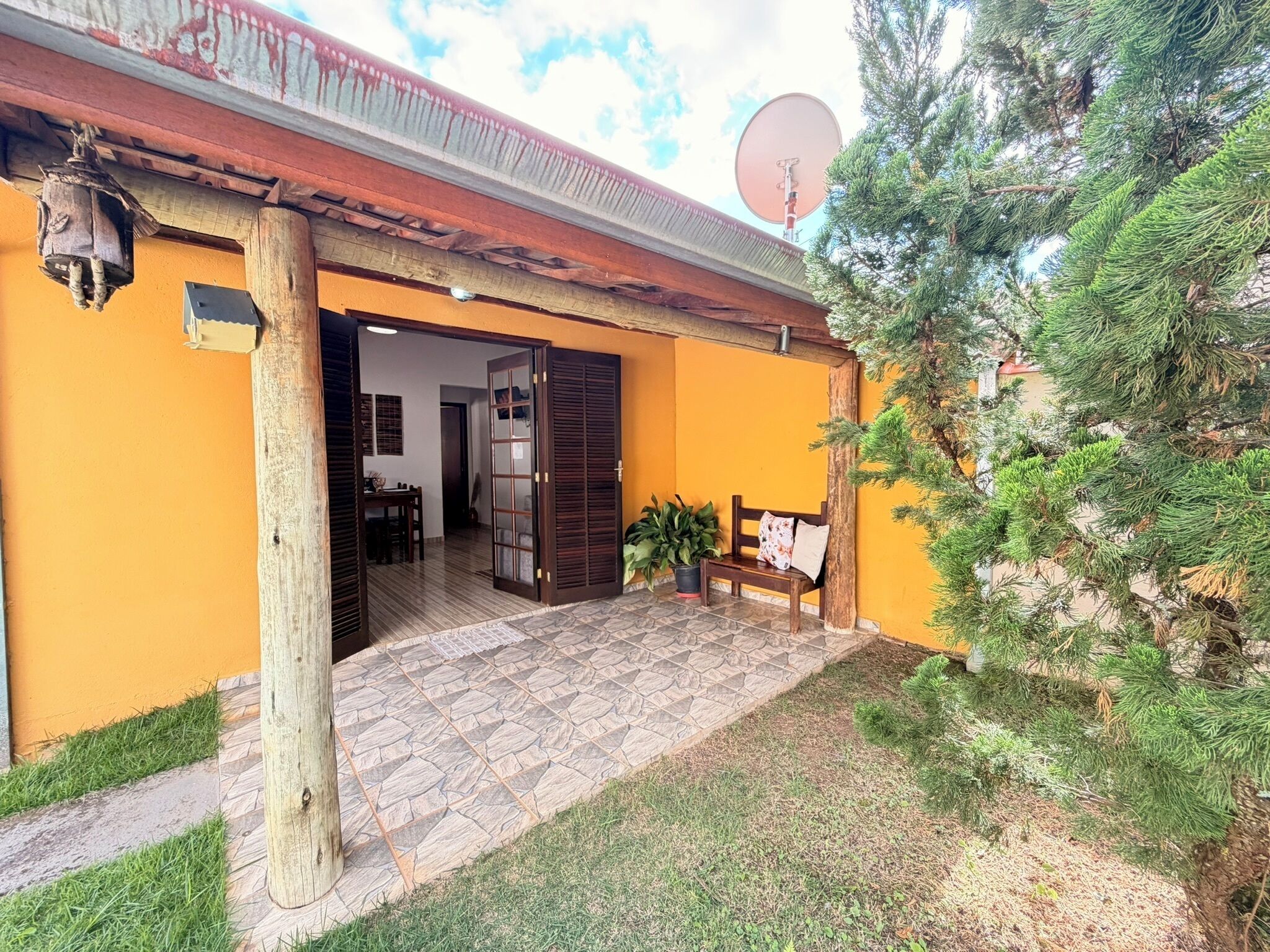 A building with a tiled entrance, a wooden bench, and a satellite dish.