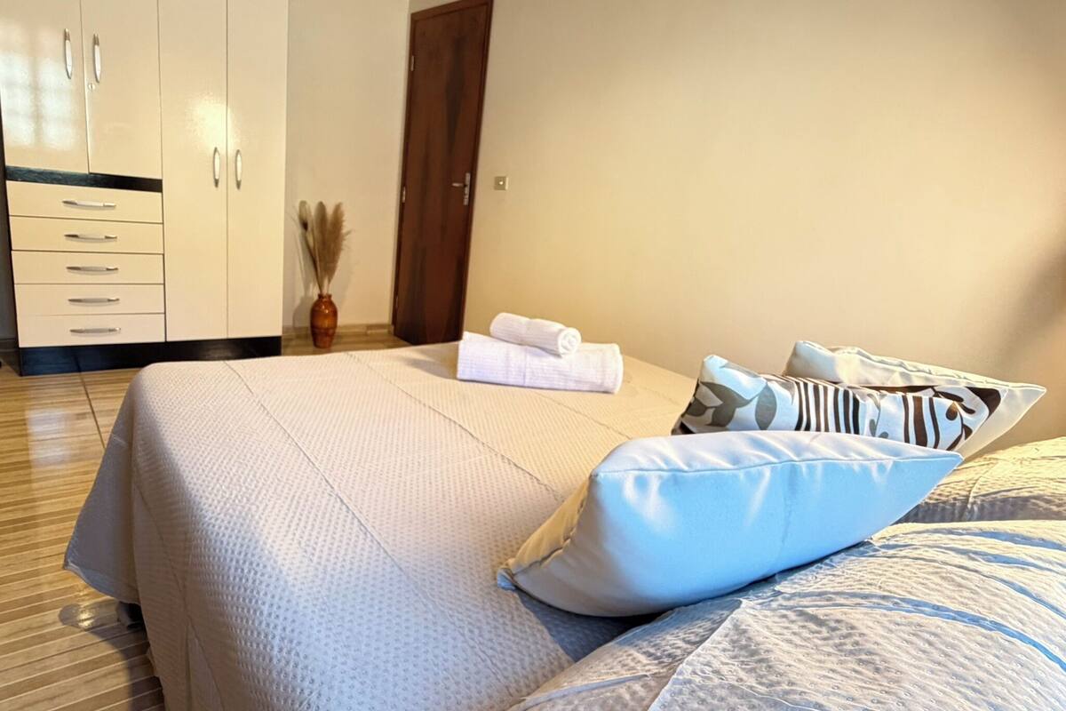 Ein Schlafzimmer mit einem Bett, Kissen, einem Holzschrank und einer Tür.