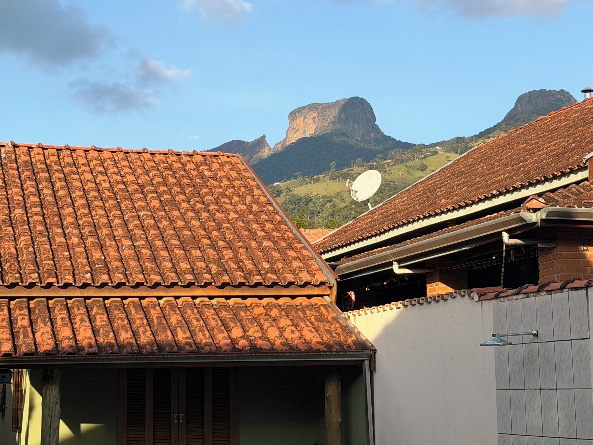 A building with a tiled roof, a satellite dish, and a mountainous backdrop.