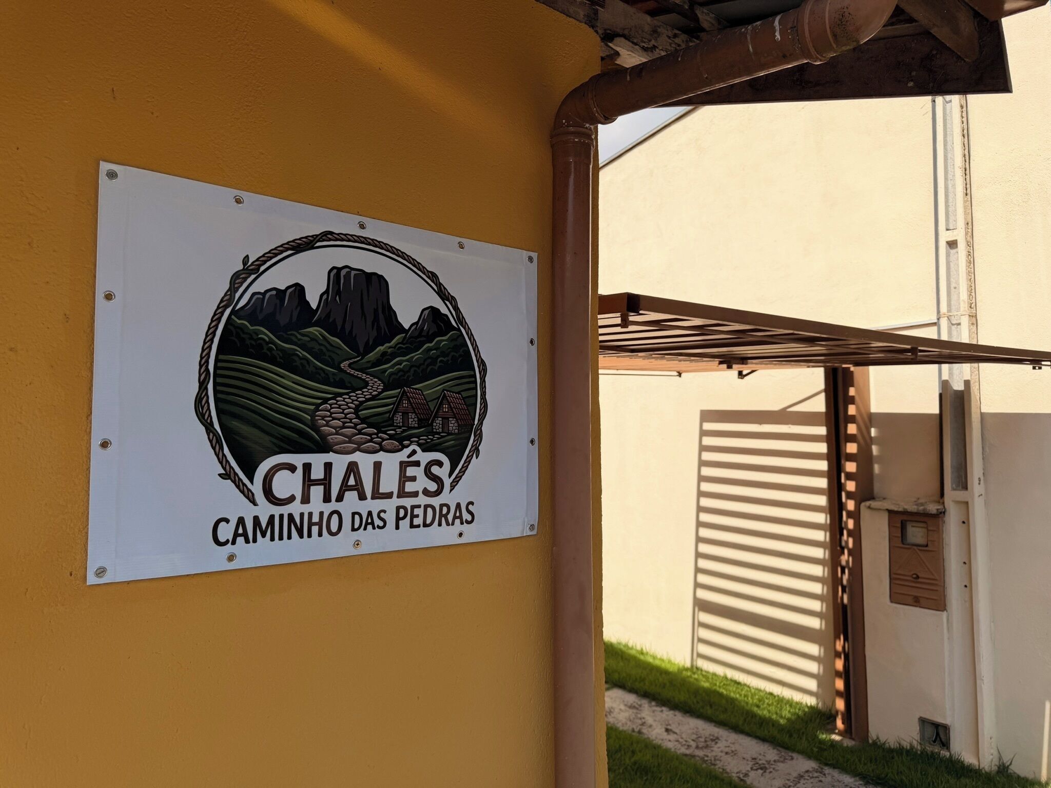 Une enseigne représentant un paysage de montagne et portant l’inscription « CHALÉ CAMINHO DAS PEDRAS ».
