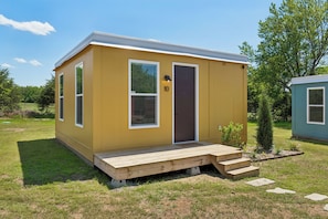 A small, single-story yellow building with a door, windows, and a small porch.