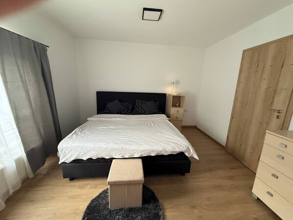 Une chambre à coucher comprenant un lit, une table de chevet, une commode, une armoire et un banc.